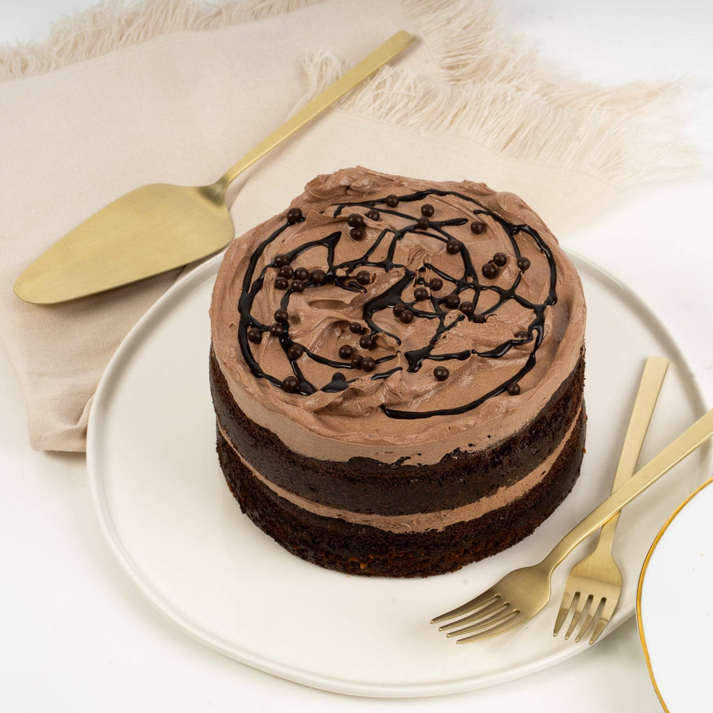 Chocolate cake with a gold spatula and forks on a white plate