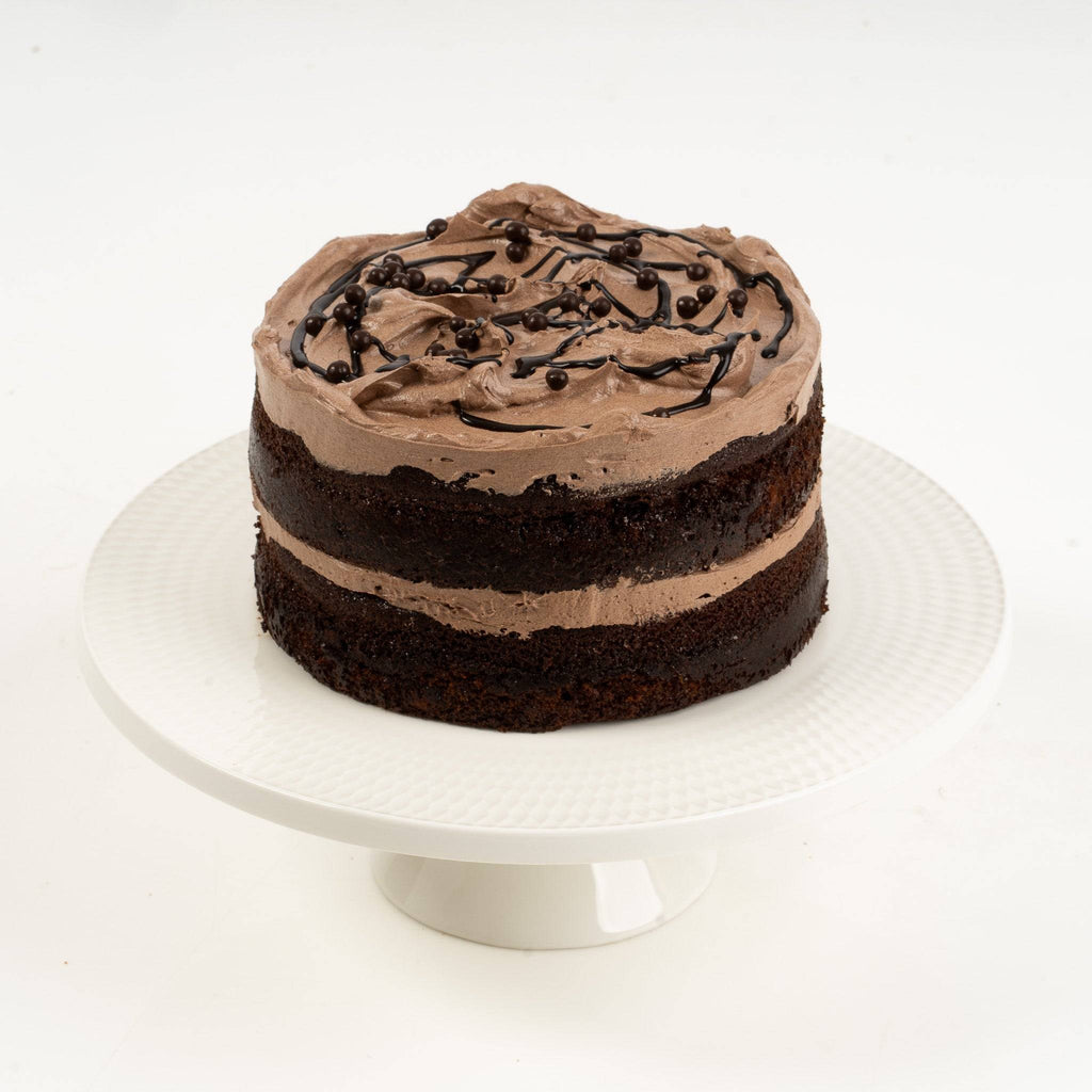 Chocolate cake on a white cake stand with a white background