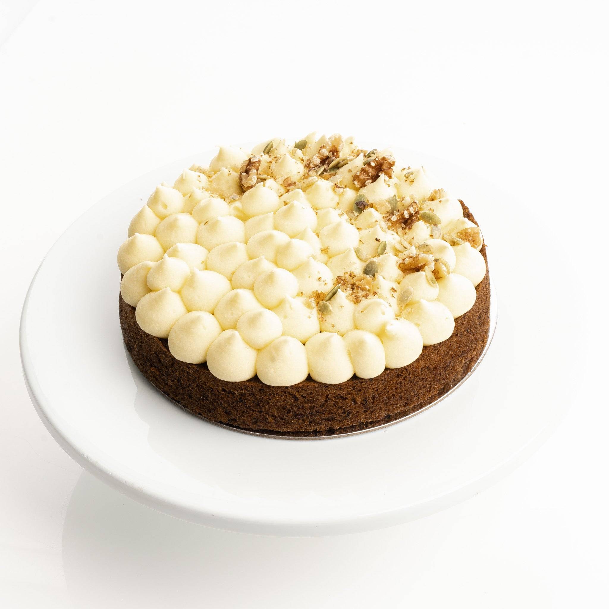 Small cake with white frosting and crumbly topping on a white plate