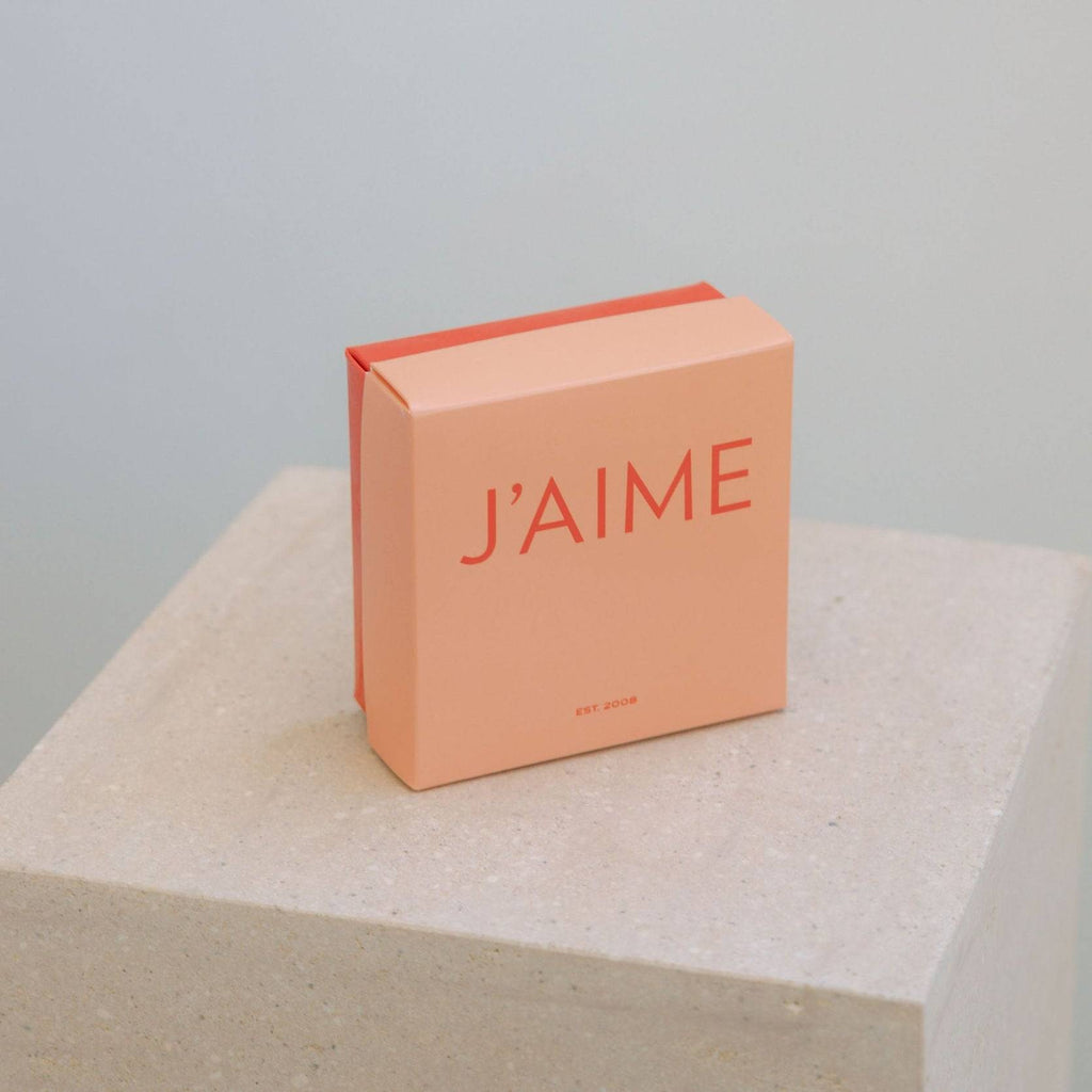 Pink box with 'J'AIME' text on a light gray background