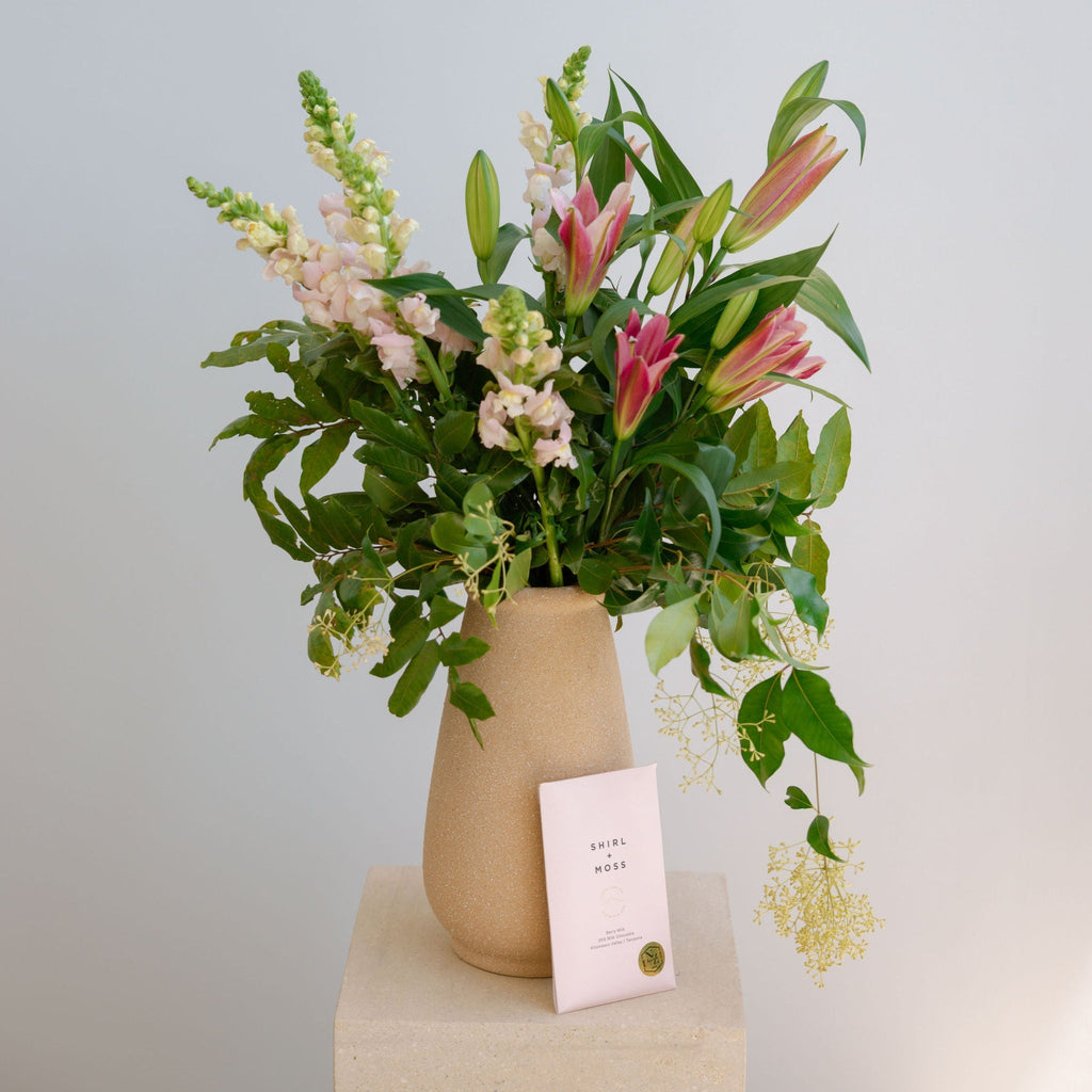 Floral arrangement in a beige vase with a light blue background