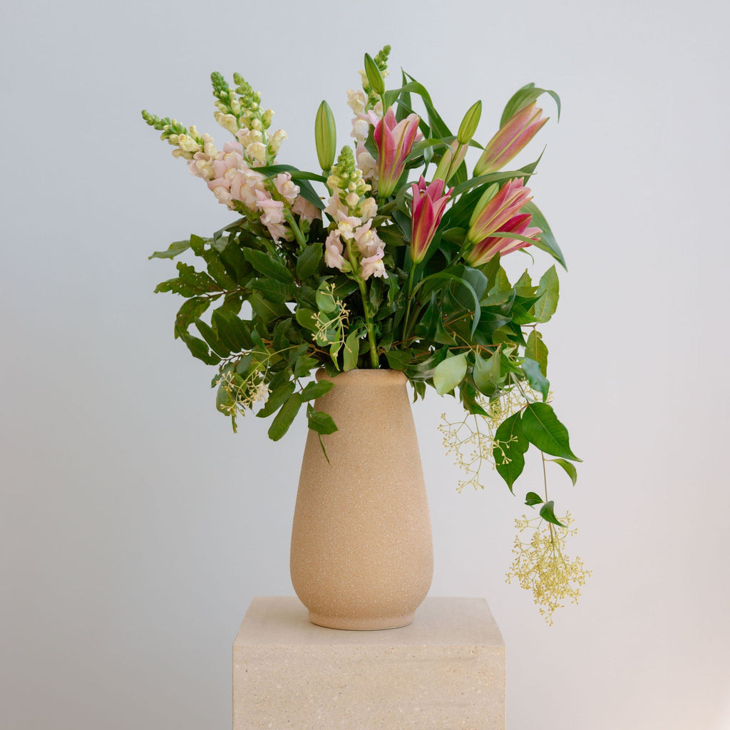 Beige vase with a bouquet of flowers on a light gray background