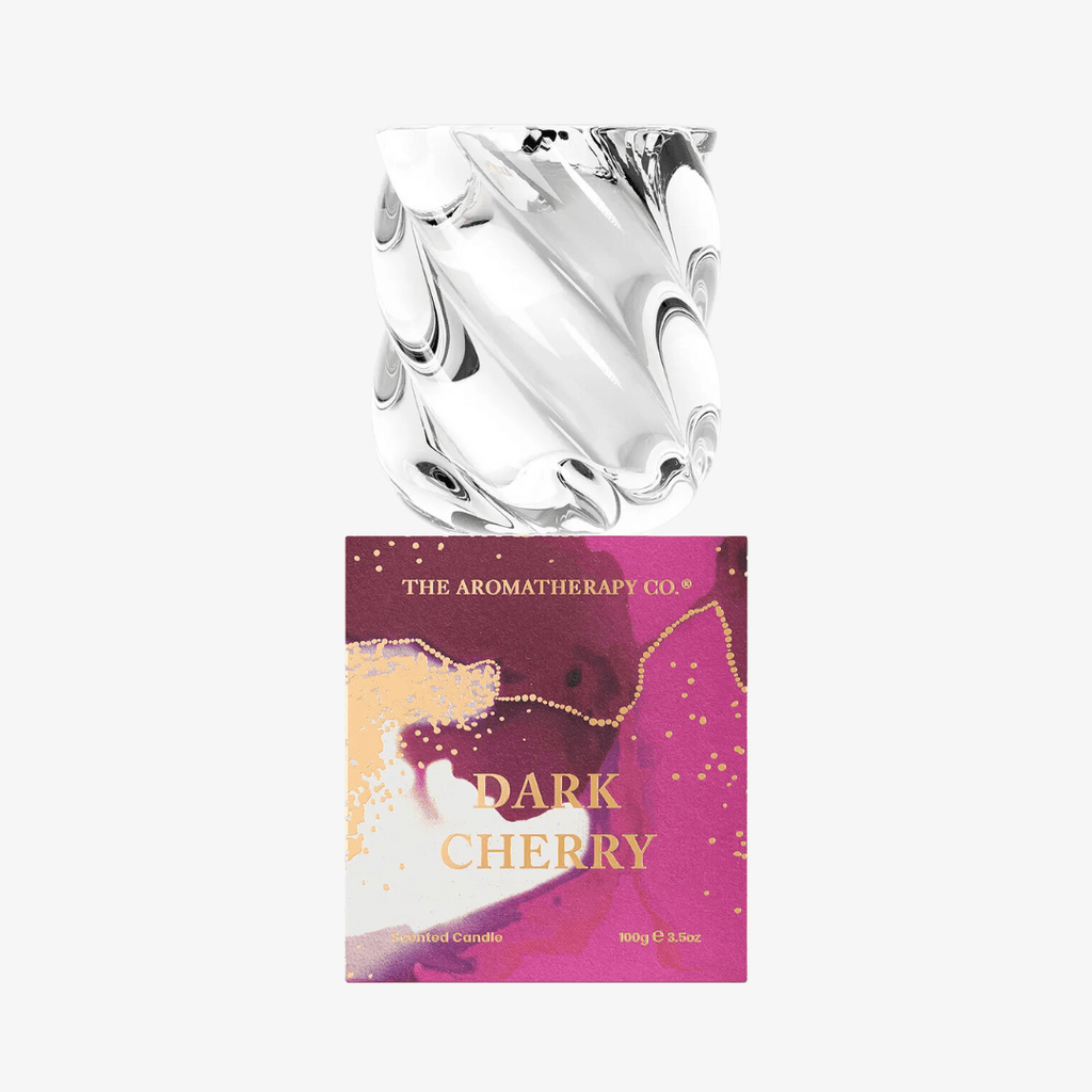 The Aromatherapy Co. Dark Cherry Candle with artistic purple and gold packaging and a sculptural glass lid, ideal for luxury home fragrance decor.